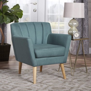 Teal chair with channel tufted back and arms with splayed wood legs and teal fabric.