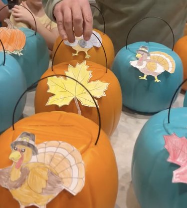 Blue and orange plastic pumpkins arranged on a table with turkey and leaf decorations on them