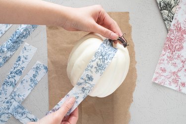 Gluing toile tissue paper onto faux pumpkins