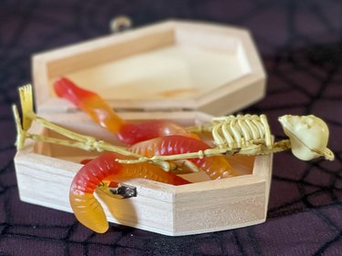 gummy worms crawling around a plastic skeleton in a casket