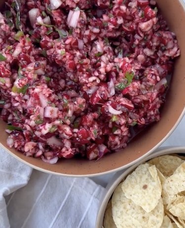 Bowl of cranberry salsa next to bowl of tortilla chips