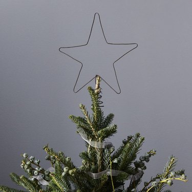 Minimalist wire star tree topper on top of a Christmas tree.
