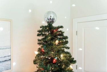 Disco ball on top of a Christmas tree reflecting light around the room.