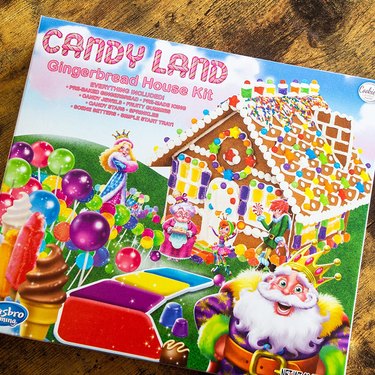 Candy Land gingerbread house kit, shown in its retail packaging against a brown tabletop