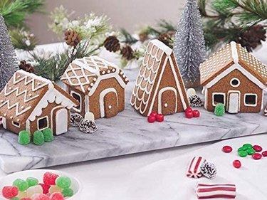 Village of miniature gingerbread houses on a marble slab with Christmas decorations