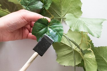 Applying decoupage to leaf with a foam brush