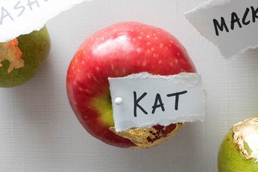 Name tag pinned to an apple with gold leaf