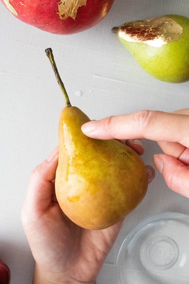 Applying water to pear in preparation for gold leaf