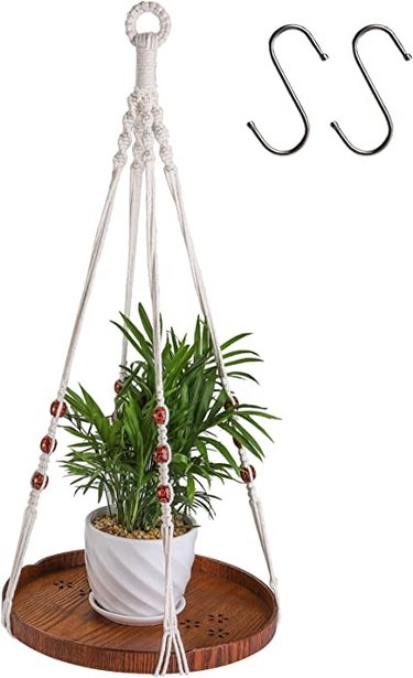 This stylish macrame plant hanger is 26 inches long and has a floating oiled chestnut shelf.