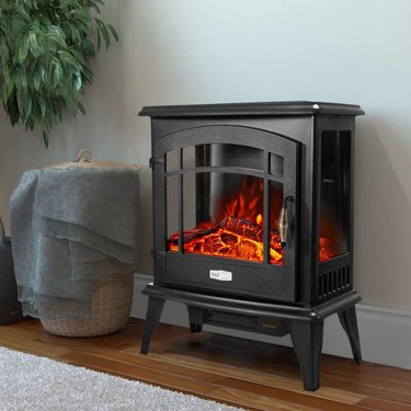 Electric fireplace heater with glass on three sides and a metal-looking finish.