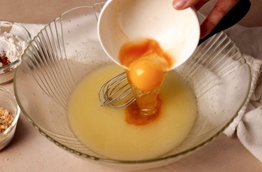 Adding an egg and vanilla to mixing bowl