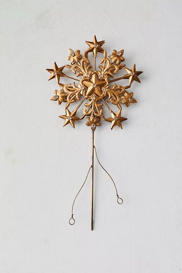Ornate gold tree topper with stars and flowers that have clear crystals in the center of each.
