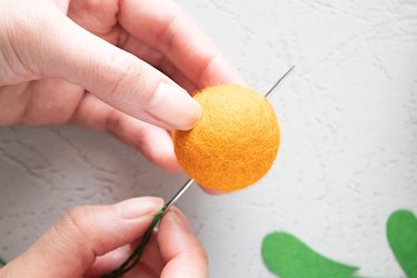 Insert needle and thread through wool felt balls