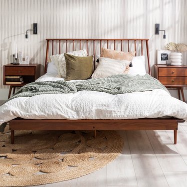 Midcentury modern walnut-colored wood queen size bed frame with a spindle headboard.