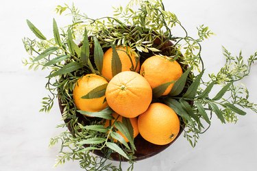 Greenery and oranges in a wooden bowl