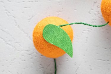 Add a green paper leaf to each wool felt ball