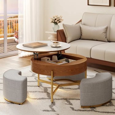 Lift top coffee table with faux marble top, wood base, and gold legs with three ottomans that you can sit on and a storage compartment inside the table.