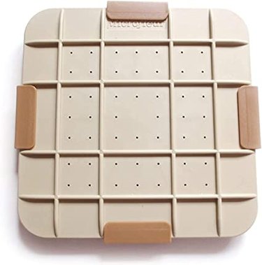 A light tan plastic square with dark tan clips around the side.
