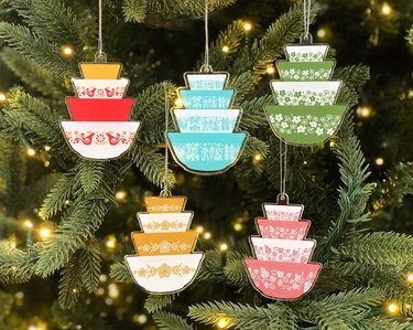 Five acrylic ornaments shaped like stacks of Pyrex dishes: one yellow and white set, one pink and white set, one blue and white set, one green and white set and one red, yellow and white set.