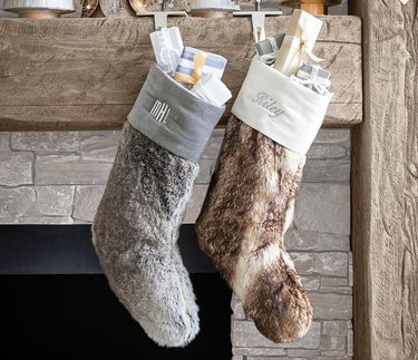 Two faux fur stockings hanging on wooden mantel