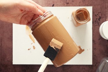 Applying light brown matte paint on a jar