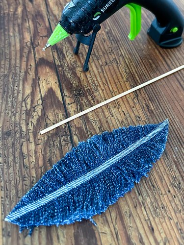 Hot glue denim feather to bamboo skewer