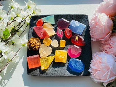 A black tray with around 20 vibrant pieces of candy that look like crystals. They're various shapes and colors, including hot pink diamonds, orange squares and yellow hearts.
