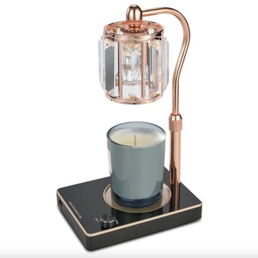 Candle warmer lamp with rose gold arm that's adjustable and a crystal glass shade.