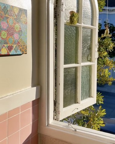 Open window to a pink tile bathroom