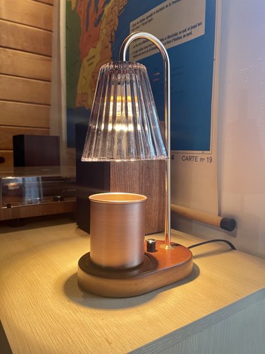 Candle warmer lamp with a fluted gray glass shade, a dark wood base, and rose gold arm.