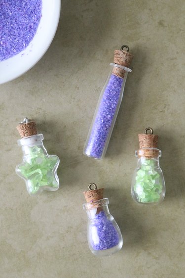 Small glass potion bottles filled with green and purple beads