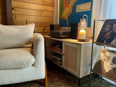 Credenza with a candle warmer lamp sitting on top of it and a boucle arm chair.