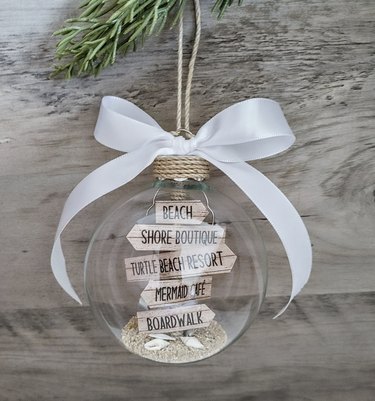 Glass ornament with beach signs inside and a white ribbon