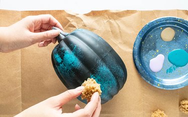 Dab teal paint on a black pumpkin with a sponge