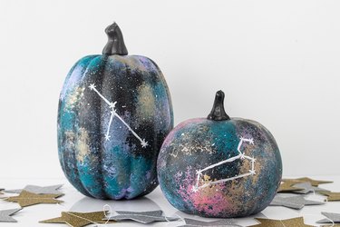 Two pumpkins painted with glitter and embellished with constellations