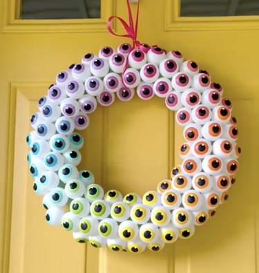 Front door wreath decorated with fake eyeballs in a rainbow of colors