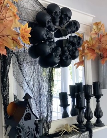 Wreath made with black faux skulls displayed on a fireplace mantel