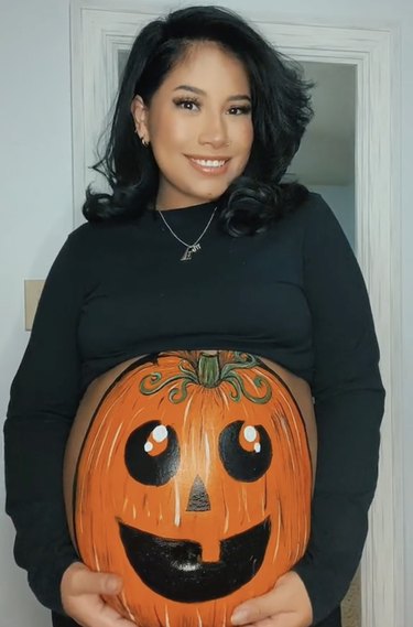 Pregnant woman with a pumpkin painted onto her belly