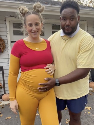 Pregnant woman dressed in orange and red outfit to resemble Winnie the Pooh next to man wearing light yellow top