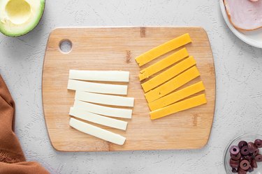 Strips of cheese on a wooden cutting board