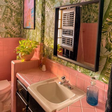 Pink tile bathroom with tropical wallpaper