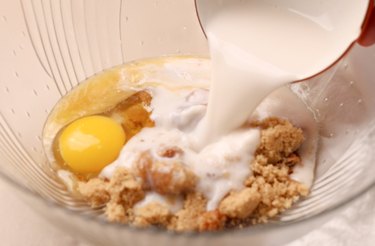 Pouring milk into a mixing bowl with other wet ingredients.