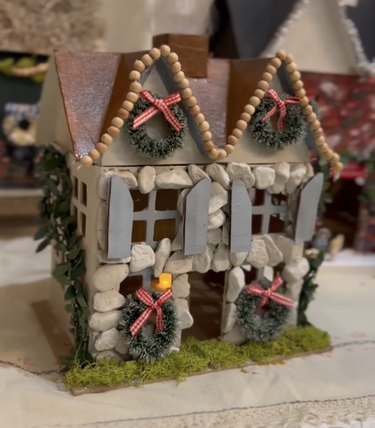 A tiny house decorated with mini wreaths and stones