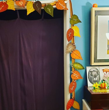 Garland of paper leaves hanging alongside a doorway next to a blue wall