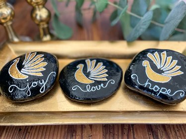 Three painted turkey gratitude rocks on a gold tray