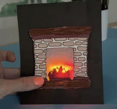 Paper card with a light-up orange fireplace design