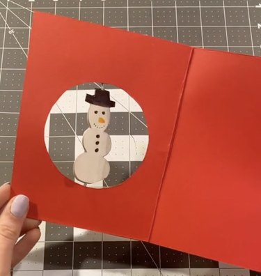 Red holiday card with a spinning white snowman in the center