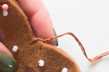 Sewing felt pretzel pieces with a blanket stitch to make an ornament