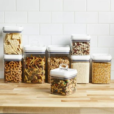 Set of 8 clear airtight dry goods storage containers on a wood countertop.