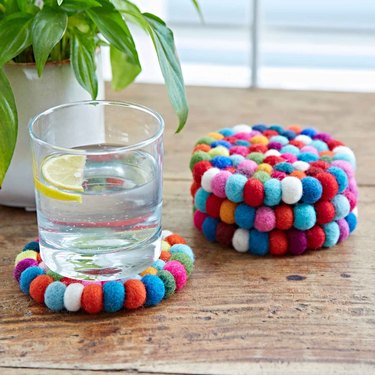 Stack of circular coasters made with rainbow pompoms